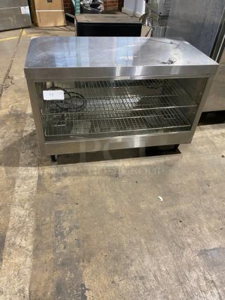 Commercial stainless steel countertop heated merchandiser display case with wired racks, on legs. Good condition.