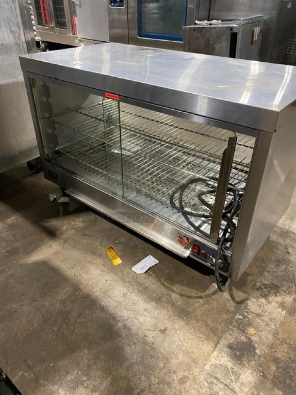 Commercial stainless steel electric countertop heated merchandiser display case with wired racks on legs, good condition.
