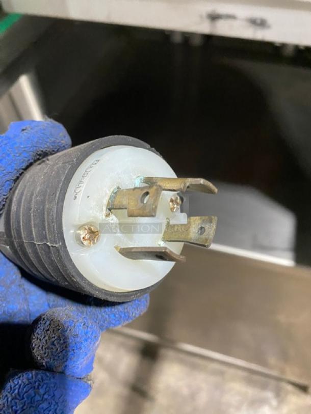 Power plug of Ilpra Koch 400VG vacuum tray sealer, showing metal prongs. Blue glove holds the plug. Condition appears used.