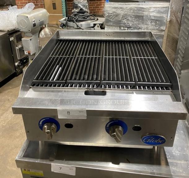 Globe commercial stainless steel natural gas countertop char broiler, serial number 1715042736, featuring control knobs, on sturdy legs.