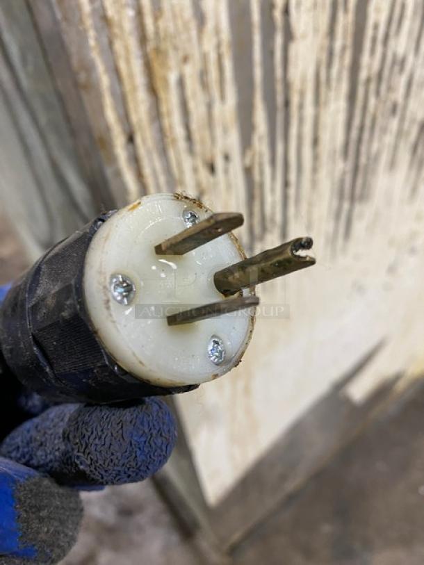 Close-up of a three-pronged electrical plug from a Manitowoc QY0454A ice machine, showing light wear.