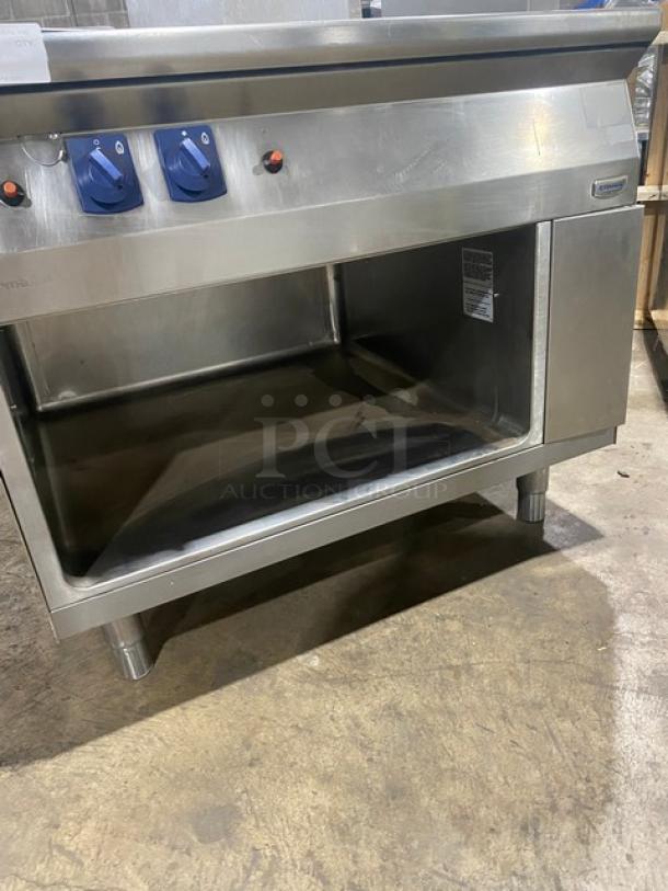 Electrolux Thermaline stainless steel flat top grill, natural gas, with backsplash, enclosed open base, on legs, knobs visible.