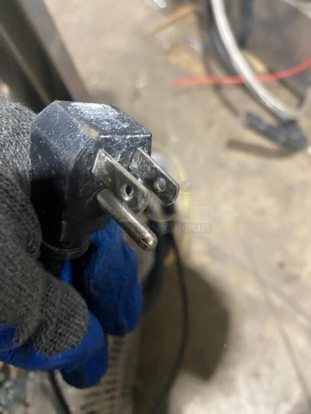 Power plug for EcoLab ULT1 dishwasher, 120V 1 Phase, shown with protective gloves in workshop setting.