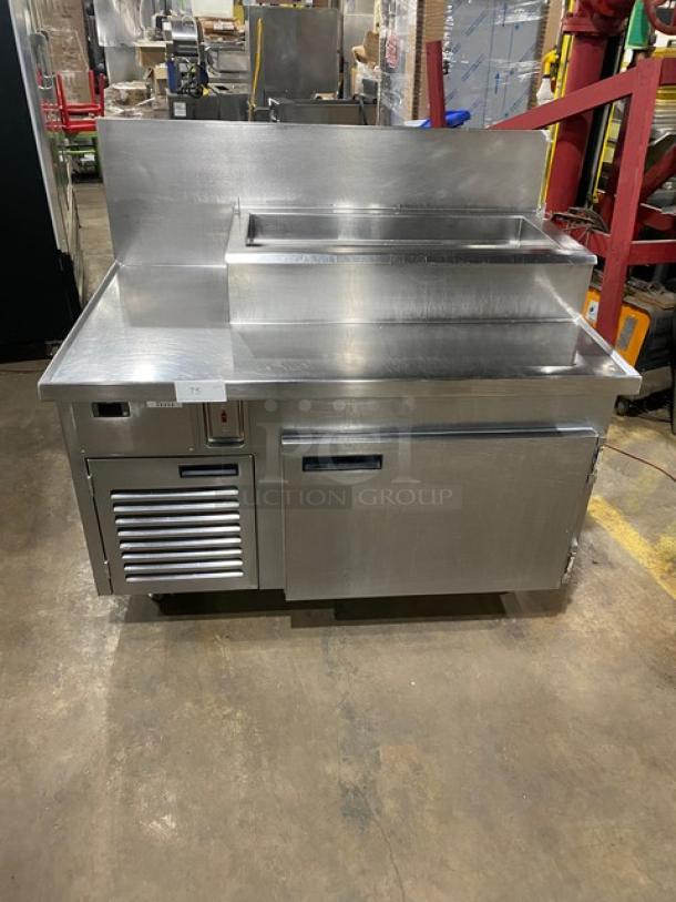 Wasserstrom stainless steel refrigerated pizza prep table, cold top railing, raised backsplash, 115V, on casters.