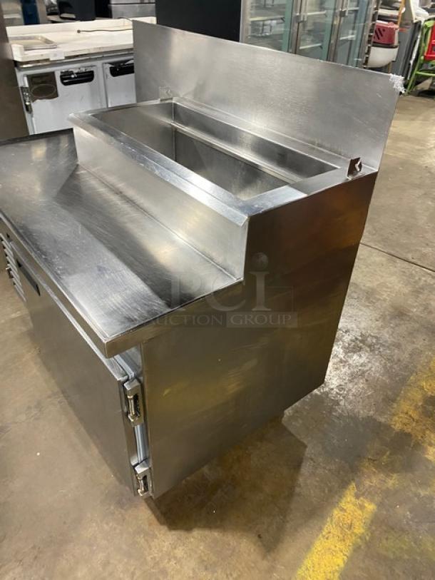 Wasserstrom stainless steel refrigerated pizza prep table, cold top railing, raised backsplash, on casters, 115V 1 phase.