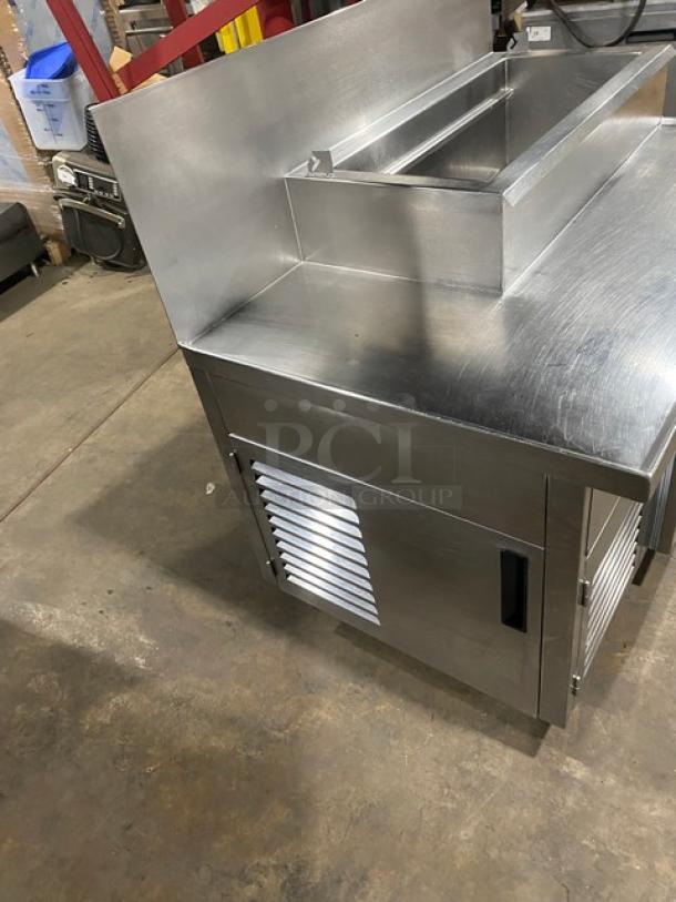 Wasserstrom stainless steel refrigerated pizza prep table with cold top railing, raised backsplash, 115V 1 phase, on casters.