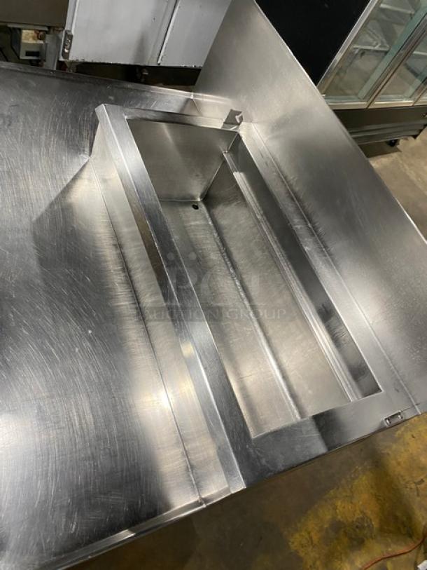 Wasserstrom stainless steel refrigerated pizza prep table with cold top railing and raised back splash, on casters.