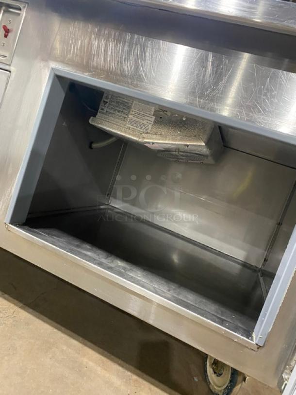 Wasserstrom stainless steel refrigerated pizza prep table with cold top railing, raised back splash, and casters. 115V, 1 Phase.