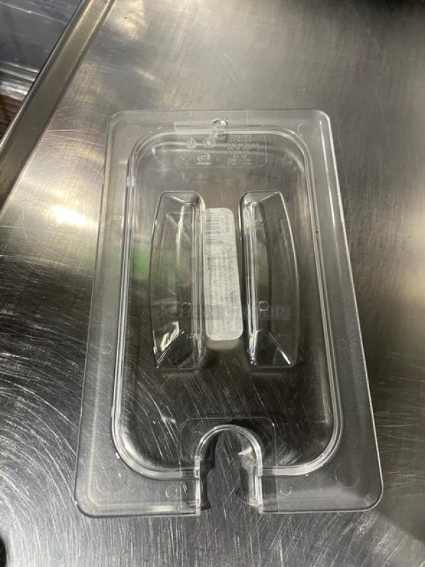 Brand new Cambro Camwear clear polycarbonate ¼-size notched food pan lid, model 40CWCHN135, on a metal surface.