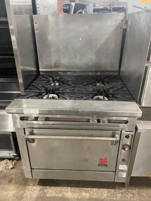 Wolf commercial stainless steel 4-burner range/oven combo, natural gas, with backsplash and wire oven rack. Appears in good condition.