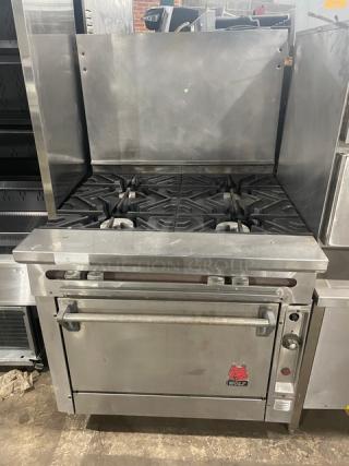 Wolf commercial stainless steel 4-burner range/oven combo, natural gas, with backsplash and wire oven rack. Appears in good condition.