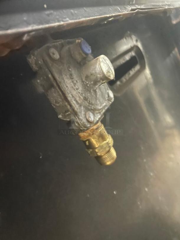 Close-up of a metal valve on a Wolf commercial stainless steel natural gas range/oven combo.