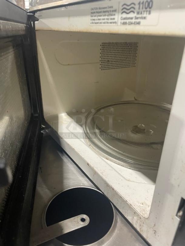 Oster Commercial Black Microwave OGZJ1104, 120V, digital controls, interior view with turntable; moderate wear.