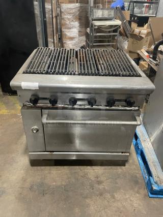 Commercial stainless steel natural gas char broiler range/oven combo with wired rack, four knobs, and robust build.
