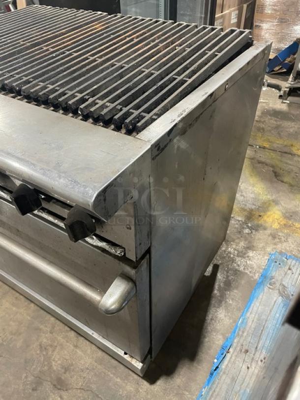 Commercial stainless steel natural gas char broiler range/oven combo with wired oven rack. Used condition, surface wear visible.