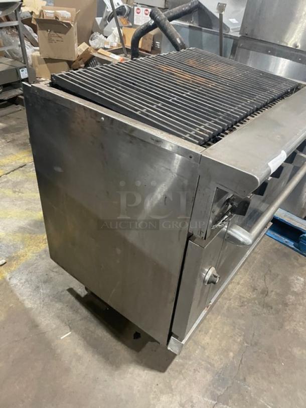 Commercial stainless steel natural gas char broiler range/oven combo with wired oven rack; visible wear, sturdy construction.