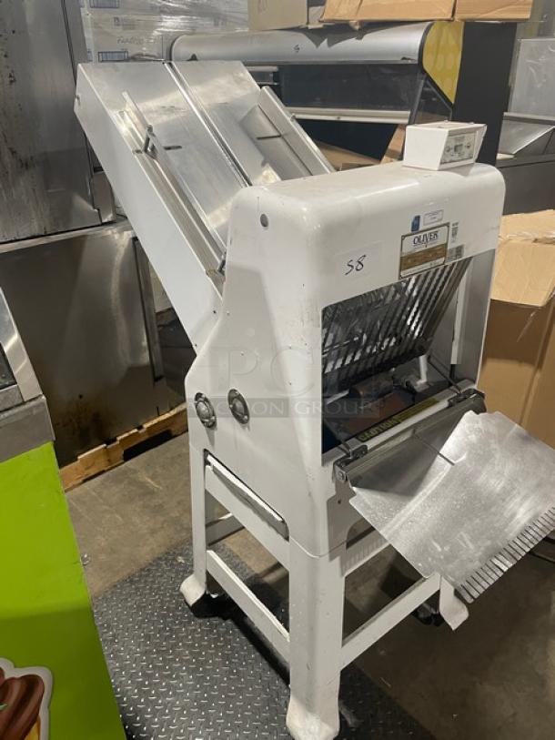 Oliver 797-32-NC white electric bread slicer, gravity feed, with stainless steel worktop, on casters, SN: 164680, 115V 1 Phase.