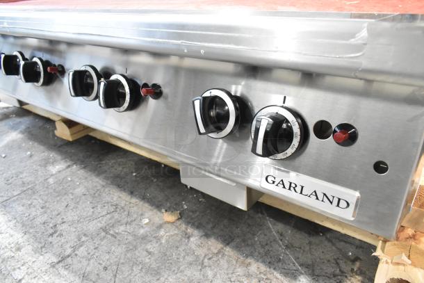 Brand new Garland stainless steel commercial countertop flat top griddle, natural gas powered, with control knobs.