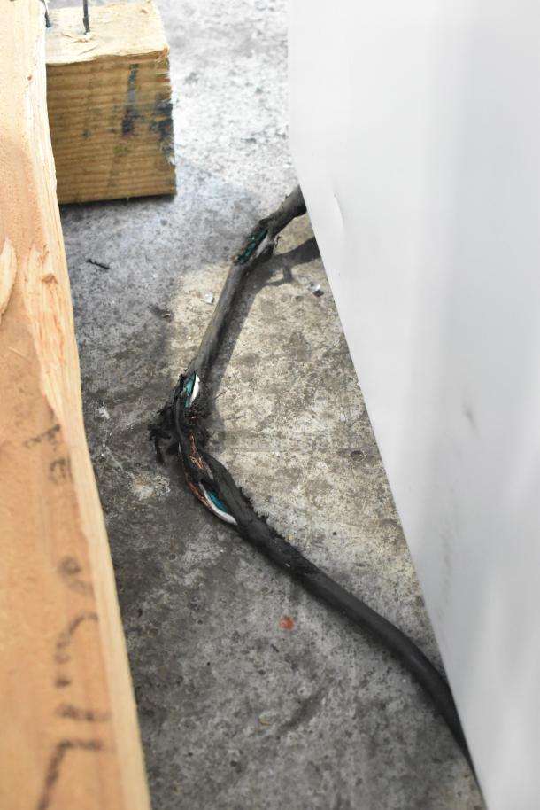 Damaged power cord on new 2021 True TSCI-600R-G-PH commercial cooler. Scratch and dent on white metal exterior.