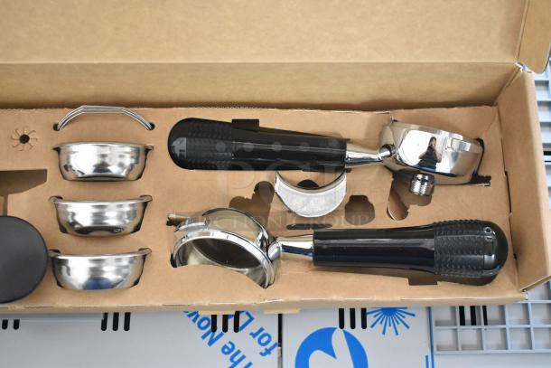Box containing new Nuova Simonelli espresso machine parts including portafilters and baskets, shown in original packaging.
