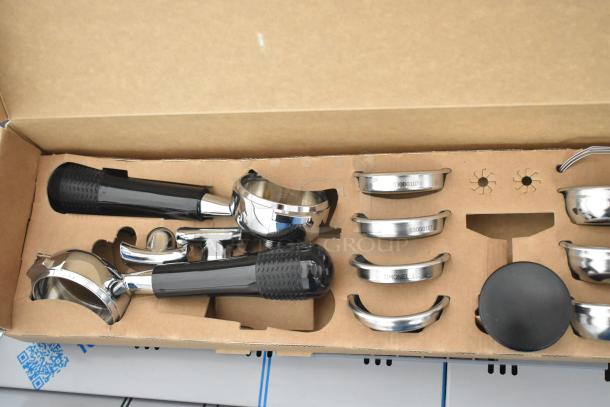Boxed accessories for Nuova Simonelli 238AUWV3 Aurelia Wave espresso machine, including portafilters and labeled baskets.