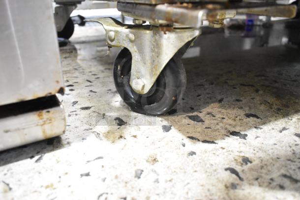 Central 69K-032HC cooler caster wheel on commercial floor; stainless steel, visible wear, supports 115V unit.