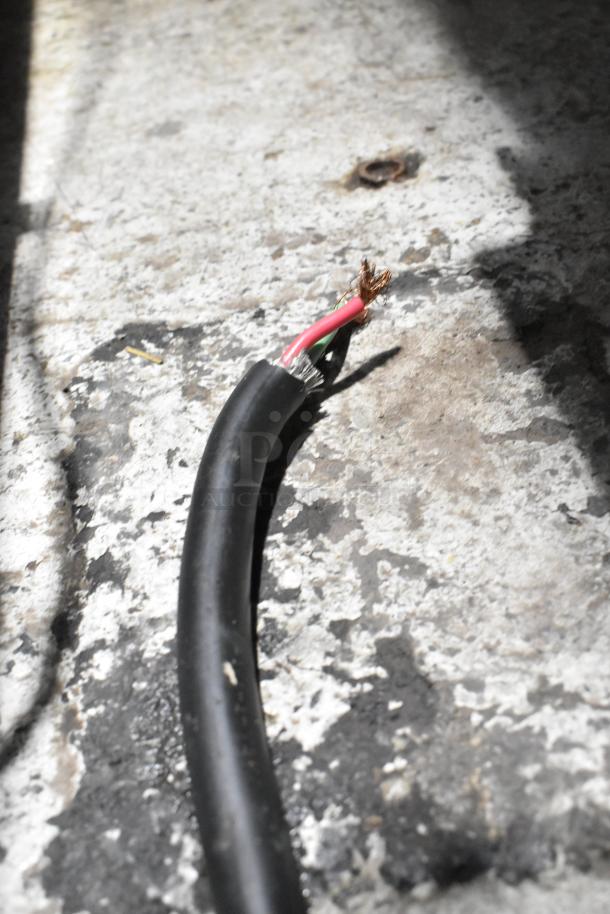 Close-up of exposed electrical wires on a damaged cable, against a textured surface.