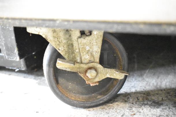 Close-up of a commercial caster wheel from the True TWT-72 stainless steel work top cooler, showing wear and rust.