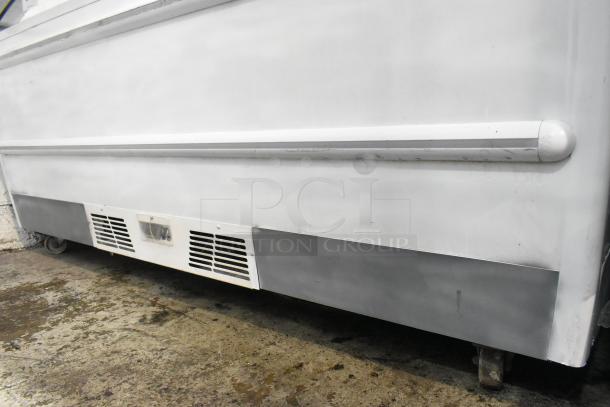 Metal commercial horizontal freezer merchandiser on casters, with cover. Used condition, visible ventilation grilles.