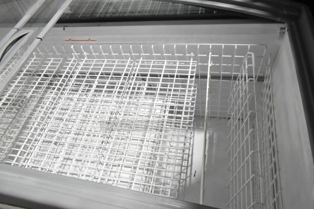 Metal commercial horizontal freezer merchandiser with cover, featuring wire baskets and commercial casters for easy mobility.