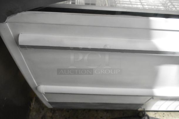 Metal commercial horizontal freezer merchandiser with cover, on commercial casters. Features include white exterior and durable design.