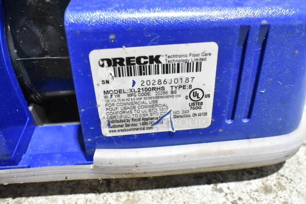 Label on Oreck XL2100RHS vacuum cleaner base, showing model number, voltage, and commercial use certification details.