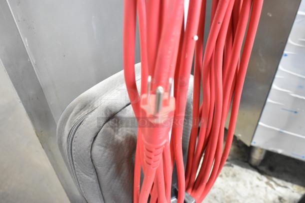Red power cord and bag attachment of Oreck XL2100RHS vacuum cleaner, showing lightweight design. Brand new, scratch and dent condition.