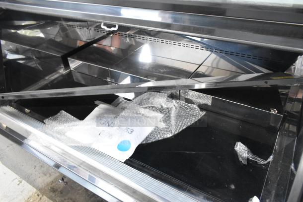 Avantco 193CAC48B black refrigerated air curtain merchandiser, 47 3/16", with bubble wrap, on commercial casters.