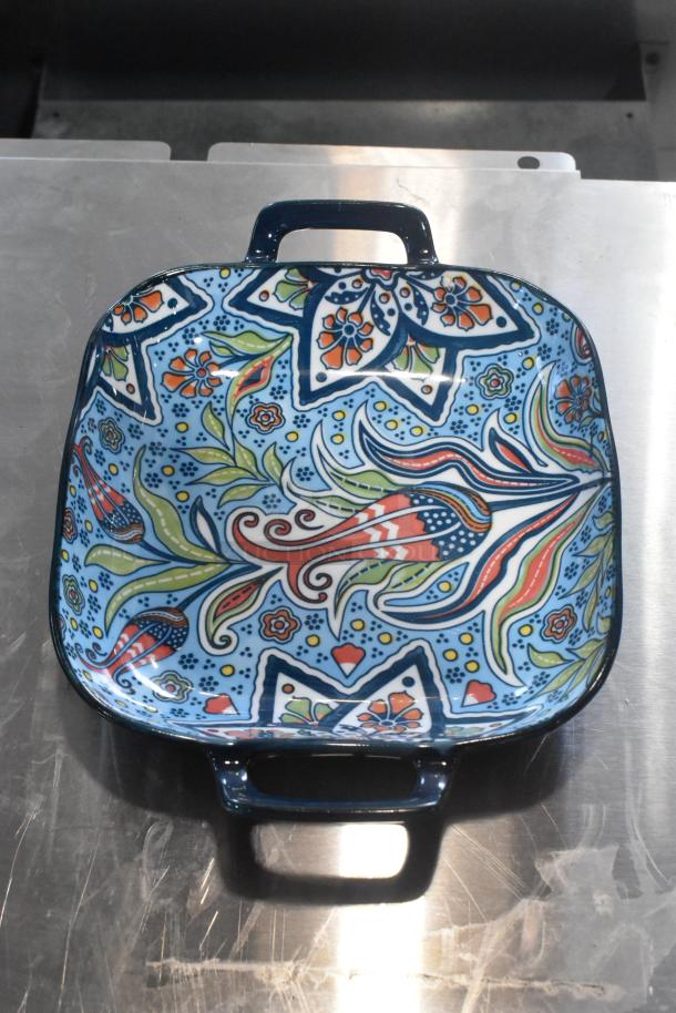 Colorful patterned dish with handles, featuring floral and geometric designs, in excellent condition.