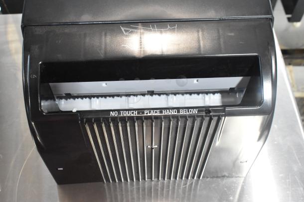 Lavex Select black poly wall mount paper towel dispenser, no-touch design, minor surface marks, "No Touch - Place Hand Below" label.