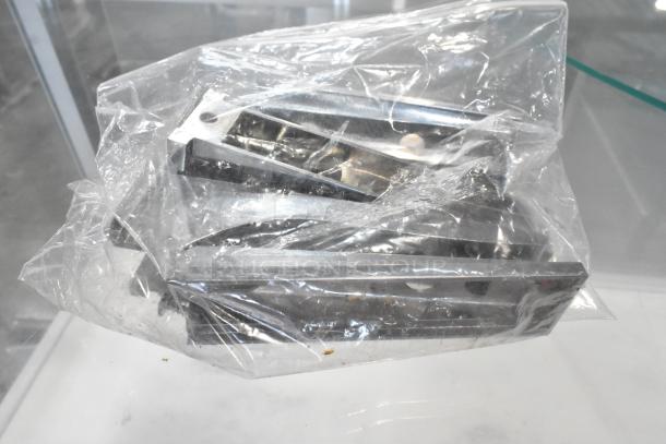 Plastic-wrapped metal brackets or components displayed, possibly related to commercial merchandising equipment.