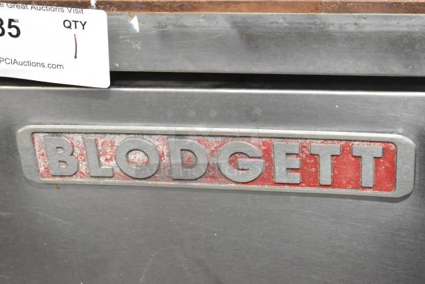 Blodgett stainless steel commercial convection oven, solid doors, metal racks, thermostatic controls, metal legs, visible logo.