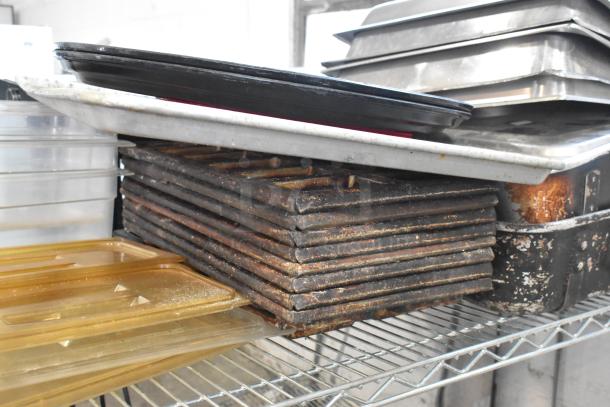 Tiered lot with metal baking pans, stainless steel drop-in bins, and poly drop-in bin lids on a wire shelf. Used condition.