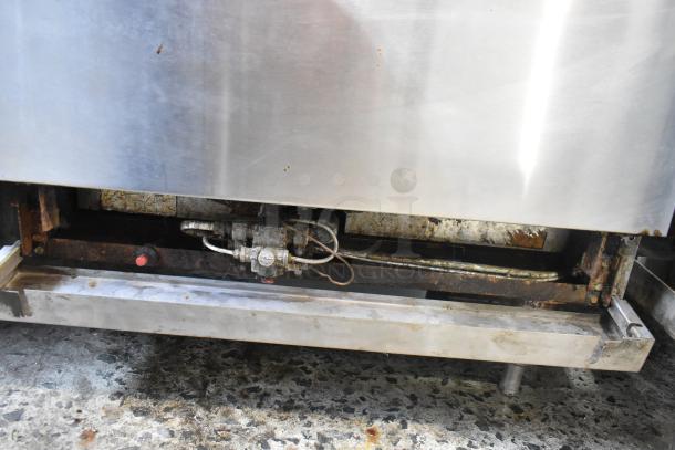 Imperial stainless steel commercial gas range undercarriage, showing gas connection and wear. Suitable for restaurant use.