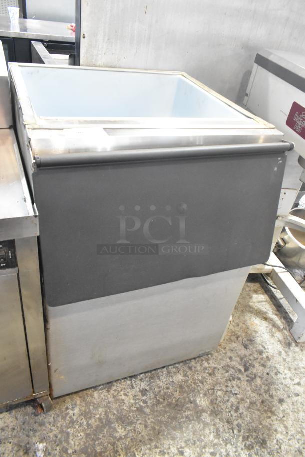 Stainless steel commercial ice bin with black exterior, showing signs of wear. Suitable for restaurant use.