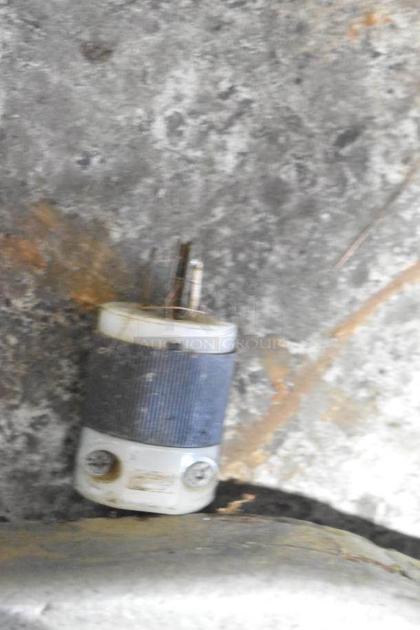 Electrical plug on a concrete floor, visible wear and discoloration. Not related to the described dough mixer.