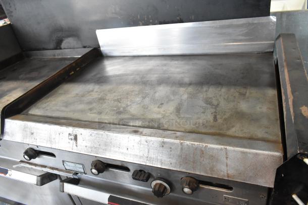 Garland stainless steel commercial gas griddle with two sections, ovens, over shelf, and backsplash. Used condition.