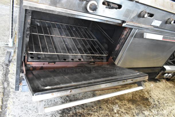 Garland stainless steel commercial gas griddle with two sections, two ovens, overshelf, backsplash; open oven door view.