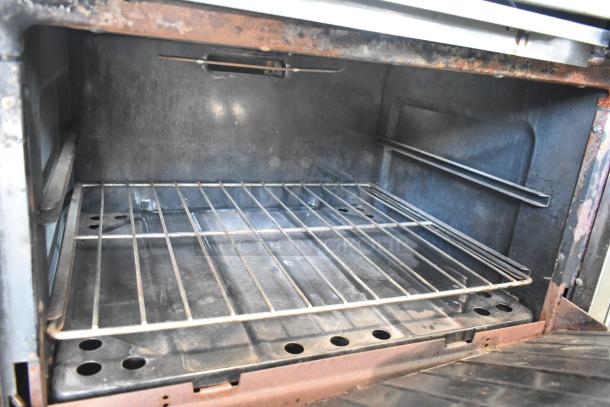 Garland stainless steel commercial gas griddle with two sections and ovens, featuring an over shelf and back splash, clean interior.