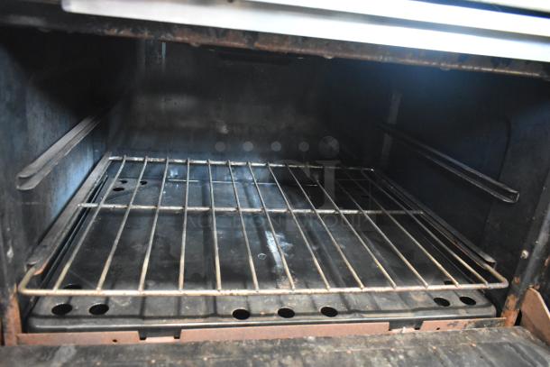 Garland stainless steel commercial gas-powered griddle oven interior, showing a clean wire rack and dark cooking surfaces.