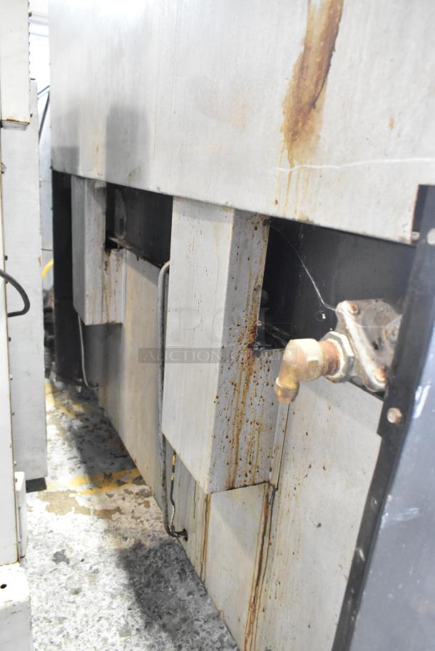 Garland stainless steel commercial gas griddle with two sections, ovens, overshelf, backsplash. Visible wear and rust.