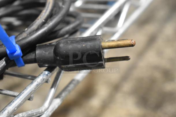 The image shows a close-up of a power plug, not the CAS AP-1 scale. The plug is black with a blue tie securing its cord.