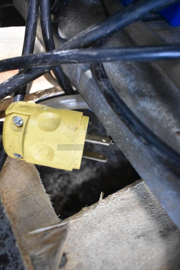 Alt text: Close-up of Master-Bilt merchandiser power cord, yellow plug, amidst cables, highlighting equipment details. Missing one side panel.