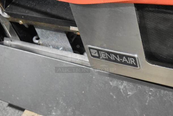Jenn-Air stainless steel commercial 6 burner range with oven, over shelf, and backsplash, featuring Jenn-Air logo.